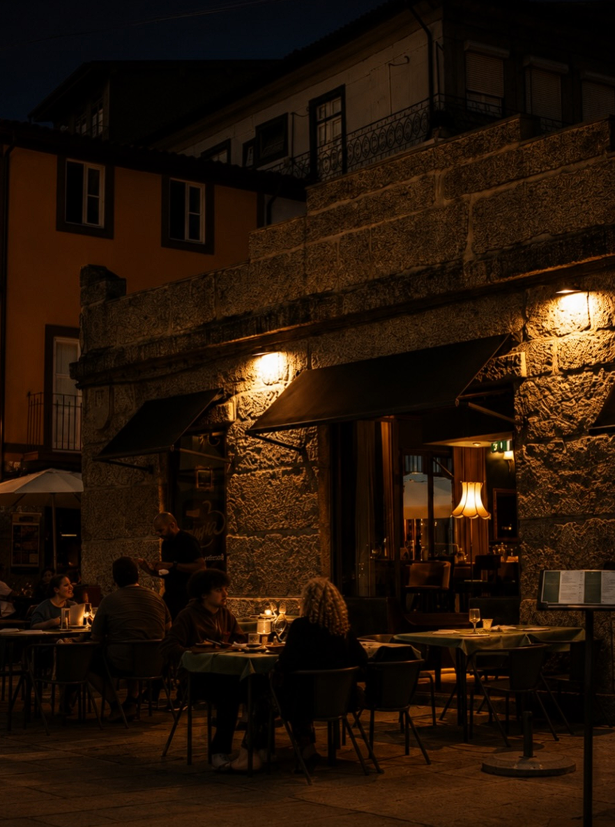 Esplanada e fachada em pedra do ALMA Restaurante iluminadas à noite